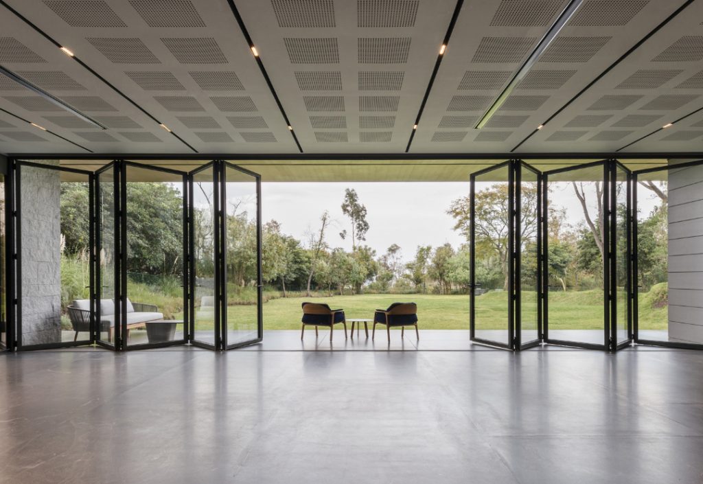 Modern interior featuring Cortizo aluminium bifold doors opening to a lush green patio, creating an indoor-outdoor living space